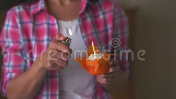 穿着格子裙的女人在室内的一个生日蛋糕上点燃蜡烛视频的预览图