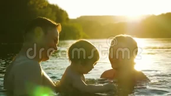 婴儿的姐姐和爸爸在金色的太阳落山中尽情地嬉戏欢笑和沐浴视频的预览图