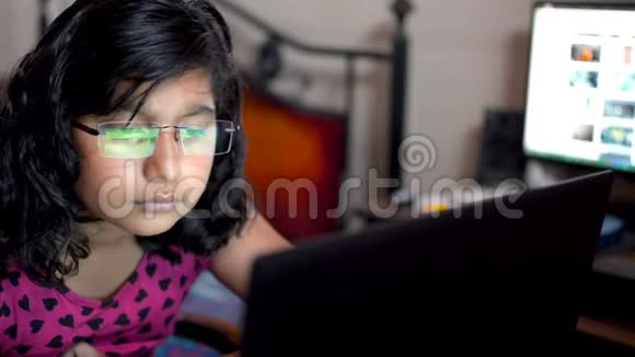 一个在家里办公室戴眼镜的印度亚裔白种人在笔记本电脑上工作关闭眼镜反光视频的预览图