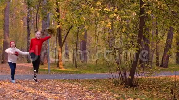 两个快乐的少女在城市公园的秋日奔跑跳跃视频的预览图