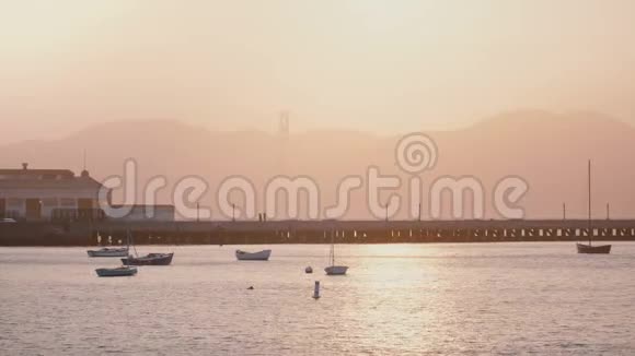 美丽的背景拍摄浪漫朦胧的旧金山日落码头与船和鸟阳光反射在海水中视频的预览图