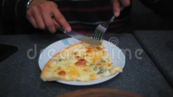 特写男性手拿刀叉在咖啡馆切披萨视频的预览图
