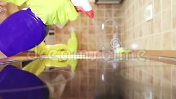 用除脂剂喷雾剂和一名戴黄色橡胶手套的妇女用吸尘器清洁厨房灶台烹饪面板视频的预览图