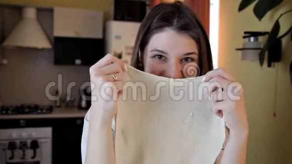 厨房里穿围裙的微笑女孩正用手撕生面团开朗的女孩笑着在周围愚弄视频的预览图