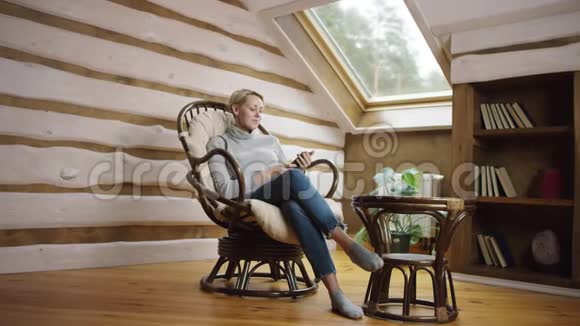 有魅力的女人坐在椅子上坐在智能手机上在社交网络上发短信视频的预览图