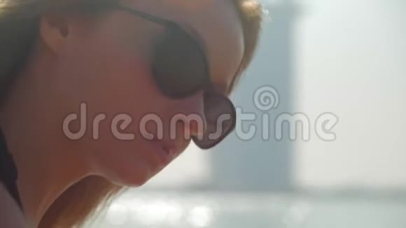 性感的年轻女孩带着太阳镜正在迪拜的一个城市公共海滩上休息特写镜头视频的预览图