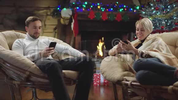 一对有智能手机的夫妇在圣诞夜大笑视频的预览图