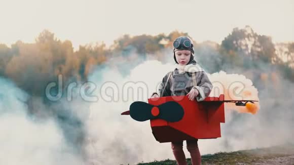 快乐的小飞行员男孩在日落湖边奔跑穿着有趣的纸板飞机服装梦想着航空事业的慢动作视频的预览图