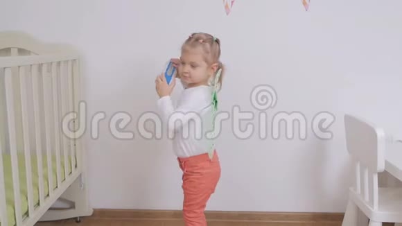 小女孩仔细听一个便携式无线蓝牙扬声器的音乐视频的预览图