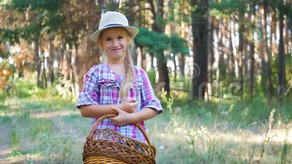 快乐的小女孩在夏天或秋天的森林里散步时采摘野生蘑菇一个带篮子和真菌的小女孩视频的预览图