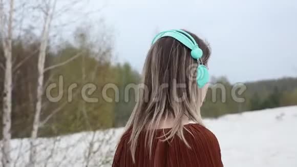 带着耳机和勃艮第色衬衫的女人穿在桦树的背景上视频的预览图
