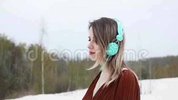 带着耳机和勃艮第色衬衫的女人穿在桦树的背景上视频的预览图