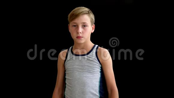 一个金发和黑眼睛的十几岁的拳击手站在黑暗的背景上少年的双手沿着身体下降视频的预览图