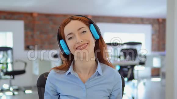 红发女商人在工作中听音乐视频的预览图