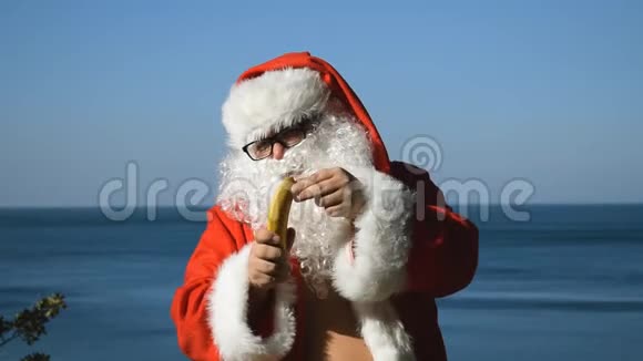 一个穿着圣诞老人服装在海滨吃香蕉的男人视频的预览图