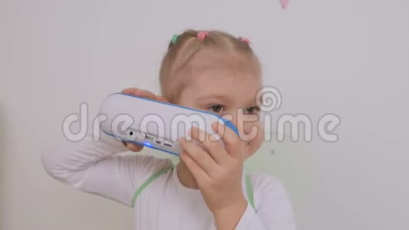 小女孩仔细听一个便携式无线蓝牙扬声器的音乐视频的预览图