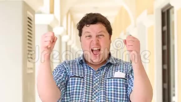 快乐成功的年轻胖子举手欢呼庆祝成功视频的预览图