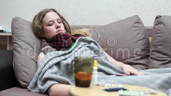 少女饮药茶暖躺在沙发上铺着毯子视频的预览图