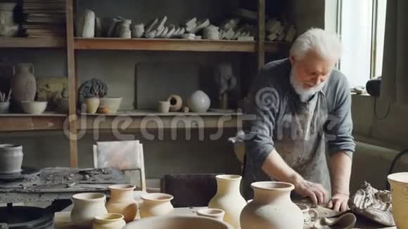 专业男性陶工是用陶工设备在小作坊里揉捏粘土形成粘土球视频的预览图