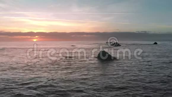 空中射击海面上的日出和岛上的火山海滩海浪和太阳出现在地平线上视频的预览图