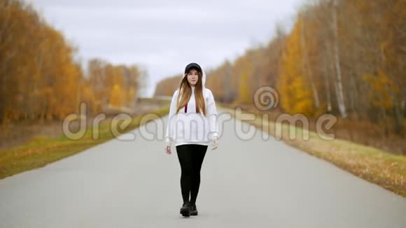 一个漂亮的年轻女人走在路中间秋天视频的预览图