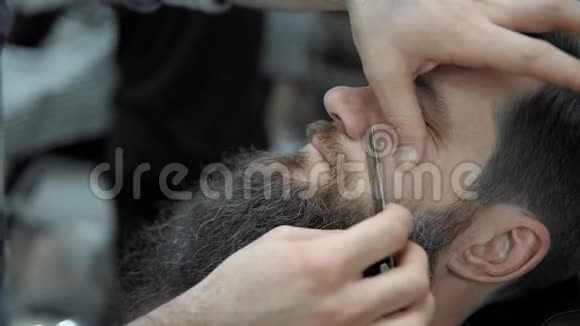 理发师在理发店或理发店用直刃剃须刀刮胡子男人理发和刮胡子视频的预览图