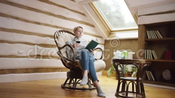 有魅力的成年女人看书在椅子上喝酒视频的预览图