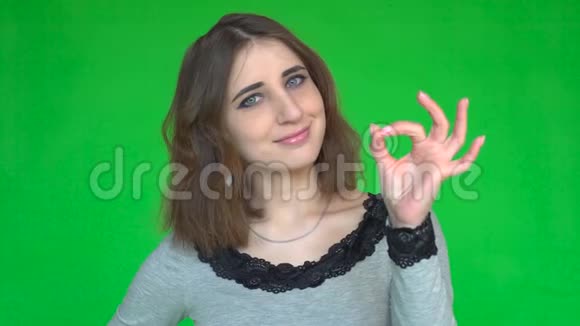 快乐的年轻女人用手指在绿色背景上隔离显示出OK标志视频的预览图