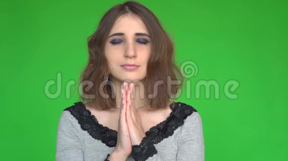 充满希望的女性在绿色的背景下在祈祷的手势中保持双手视频的预览图