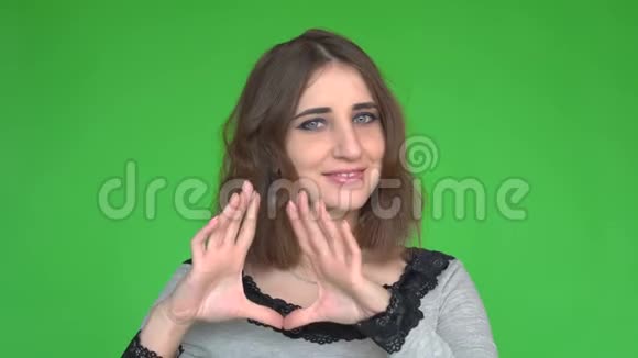 爱肖像微笑的女人做心脏标志象征用手隔离绿墙背景视频的预览图