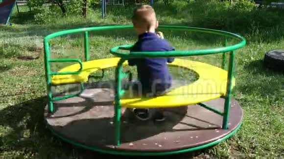 那个小男孩在公园的旋转木马上快速旋转幼儿游戏视频的预览图