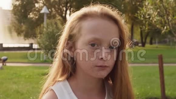 一个长着雀斑的红发小女孩在阳光明媚的夏日仰望天空视频的预览图