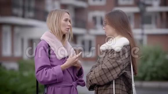 秋天两个漂亮的女人站在一座城市的生活大楼里聊天一个朋友在说话视频的预览图