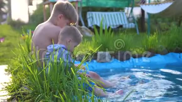 两个小朋友在一个小湖边玩湖边种花种草孩子们用水溅出来视频的预览图