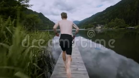 年轻人跑着跳进高山湖泊里视频的预览图