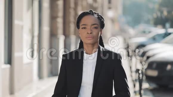 时尚的非裔美国商务女性站在老街上交叉双手的肖像她看着视频的预览图