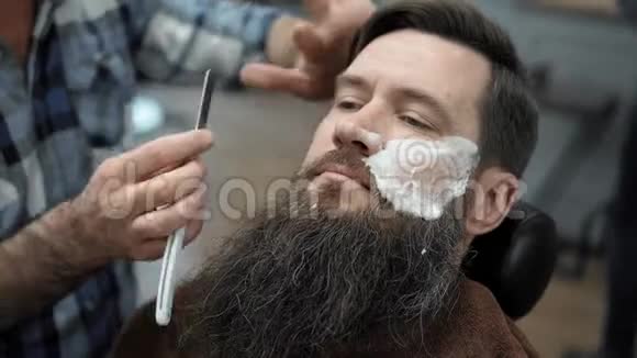 理发师在理发店或理发店用直刃剃须刀刮胡子男人理发和刮胡子视频的预览图