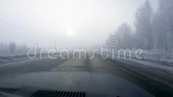 这辆汽车在覆盖着雪和浓雾的树林中行驶视频的预览图