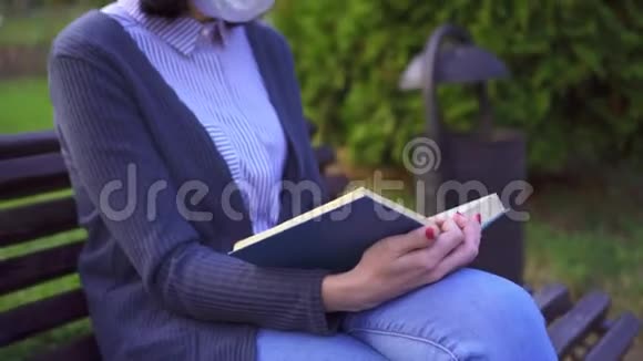 日落时分一个戴着医用防护面具的女孩和一本书在长凳上的肖像视频的预览图
