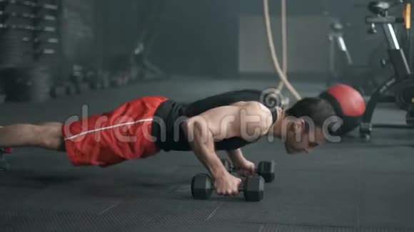 这个肌肉发达的人正在用哑铃做俯卧撑运动进行交叉配合的锻炼4K慢动作视频的预览图