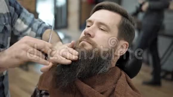 理发师和留着长胡子的成年男子理发店理发梳胡子美容师视频的预览图