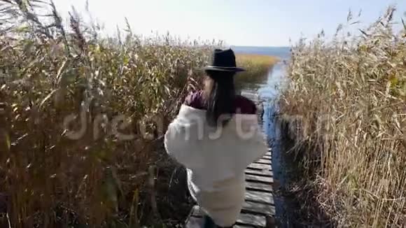 穿着帽子和毛衣的女孩沿着码头向前走视频的预览图