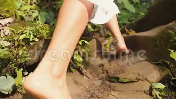 穿着白色连衣裙的小女孩赤脚走到热带雨林丛林中的小瀑布免费生活旅行4K视频的预览图