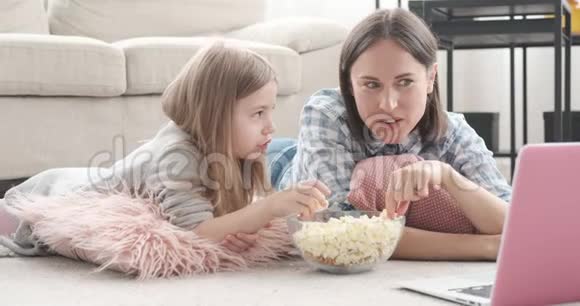 妈妈带着女儿吃爆米花和看手提电脑电影视频的预览图