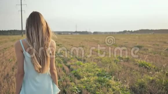 傍晚一个留着长发的小女孩赤脚穿着一件蓝色的裙子在田野里散步她举起双臂好像在飞翔视频的预览图