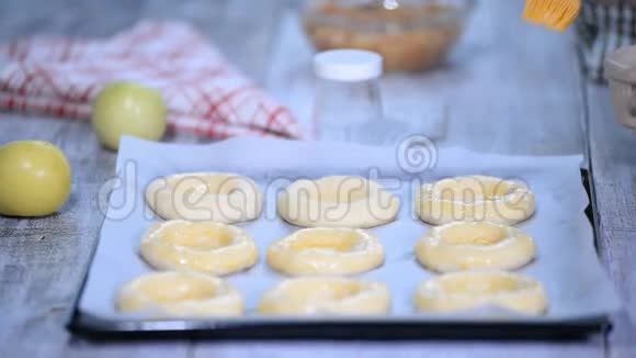 女人手用鸡蛋润滑面包用苹果Vatrushka煮开面包传统的俄罗斯烘焙系列视频的预览图