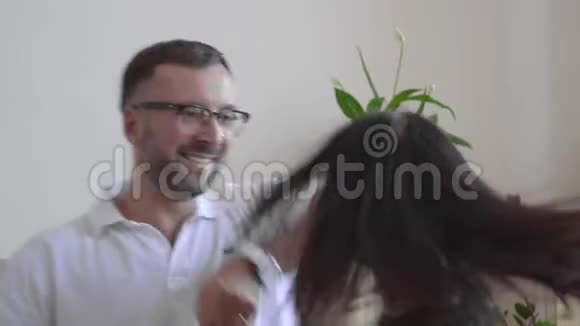 一个戴眼镜和一件白色t恤的男人和他的妻子跳舞一男一女在房间里走动手牵手关于视频的预览图