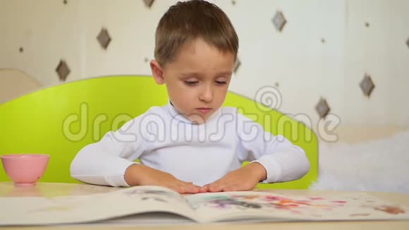一个淘气的男孩拿颜料在纸上拍掌孩子的发展教育心理情感视频的预览图