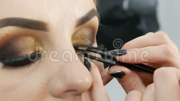 大师化妆师在美容院将专业化妆的金色烟雾眼睛应用于一个蓝眼睛的胖女人模特视频的预览图