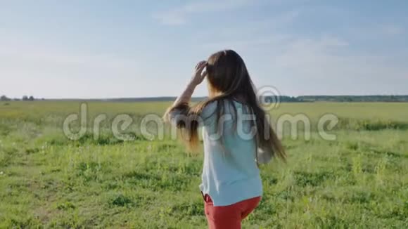 俄罗斯女孩手里拿着一束花摆姿势在一个温暖的夏天晚上在田野里奔跑视频的预览图